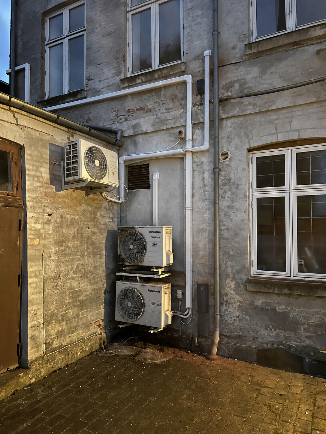 Udedele og rørføring ved en muret facade.